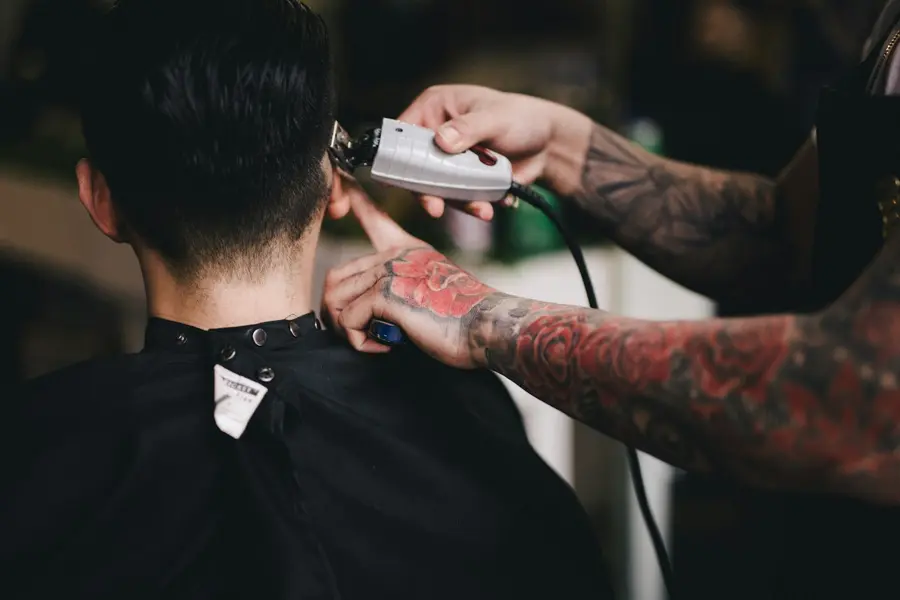 Barbero usando una máquina de cortar en la nuca de un cliente
