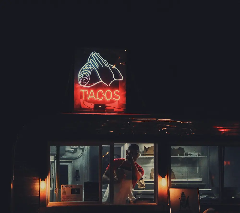Puesto de tacos de noche con letrero luminoso